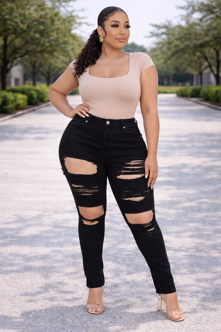 Close-up front view of black distressed skinny jeans showing ripped detail